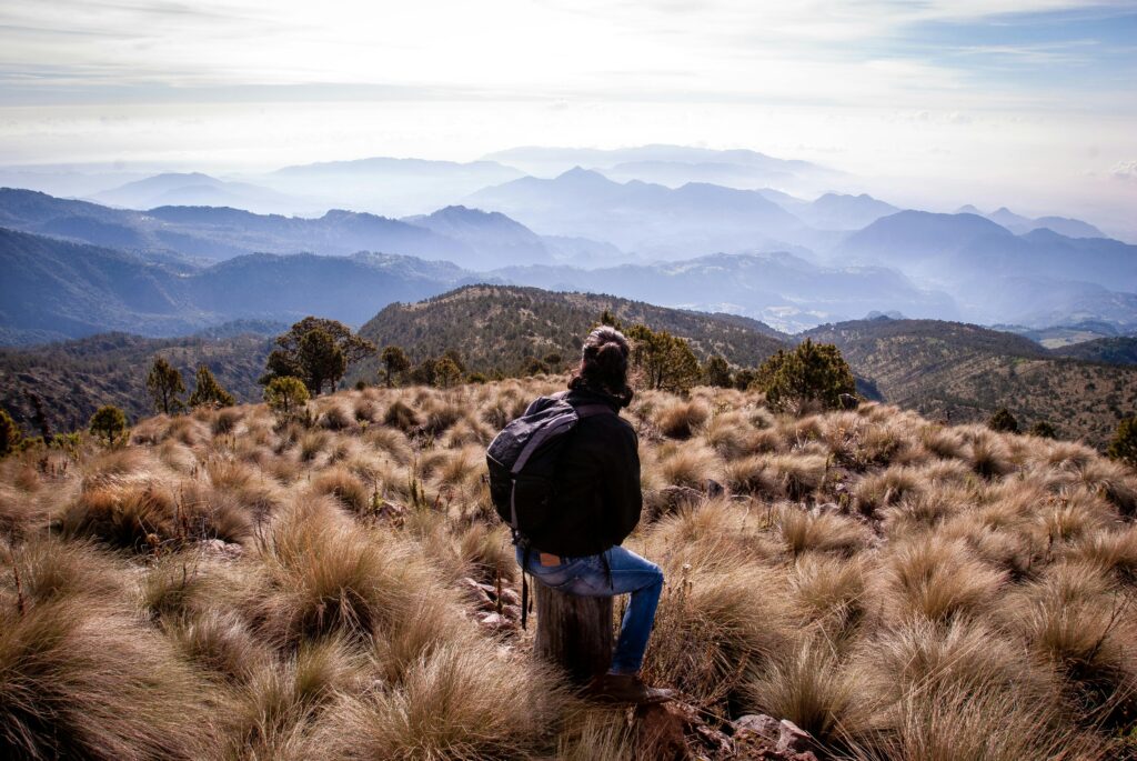 Caminante con nuestros productos recomendados de senderismo admirando las montañas durante la temporada seca